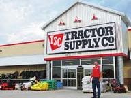 A man standing in front of a tractor supply store.