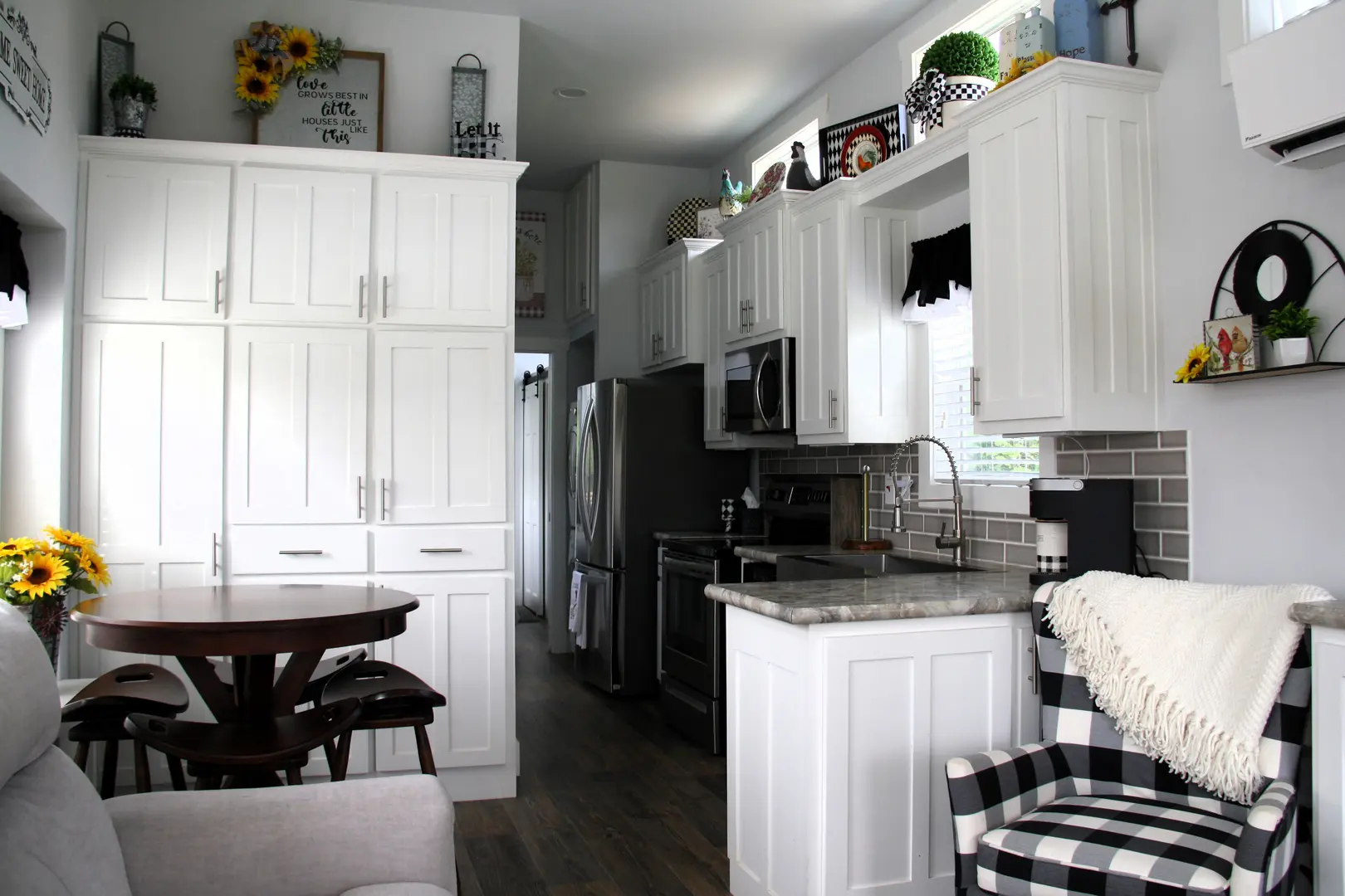 A kitchen with white cabinets and black checkered chairs.