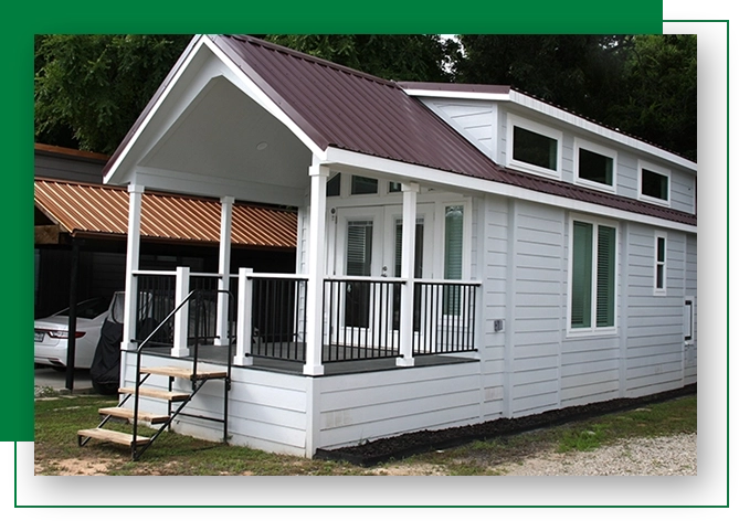 A small white house with a porch and a deck.