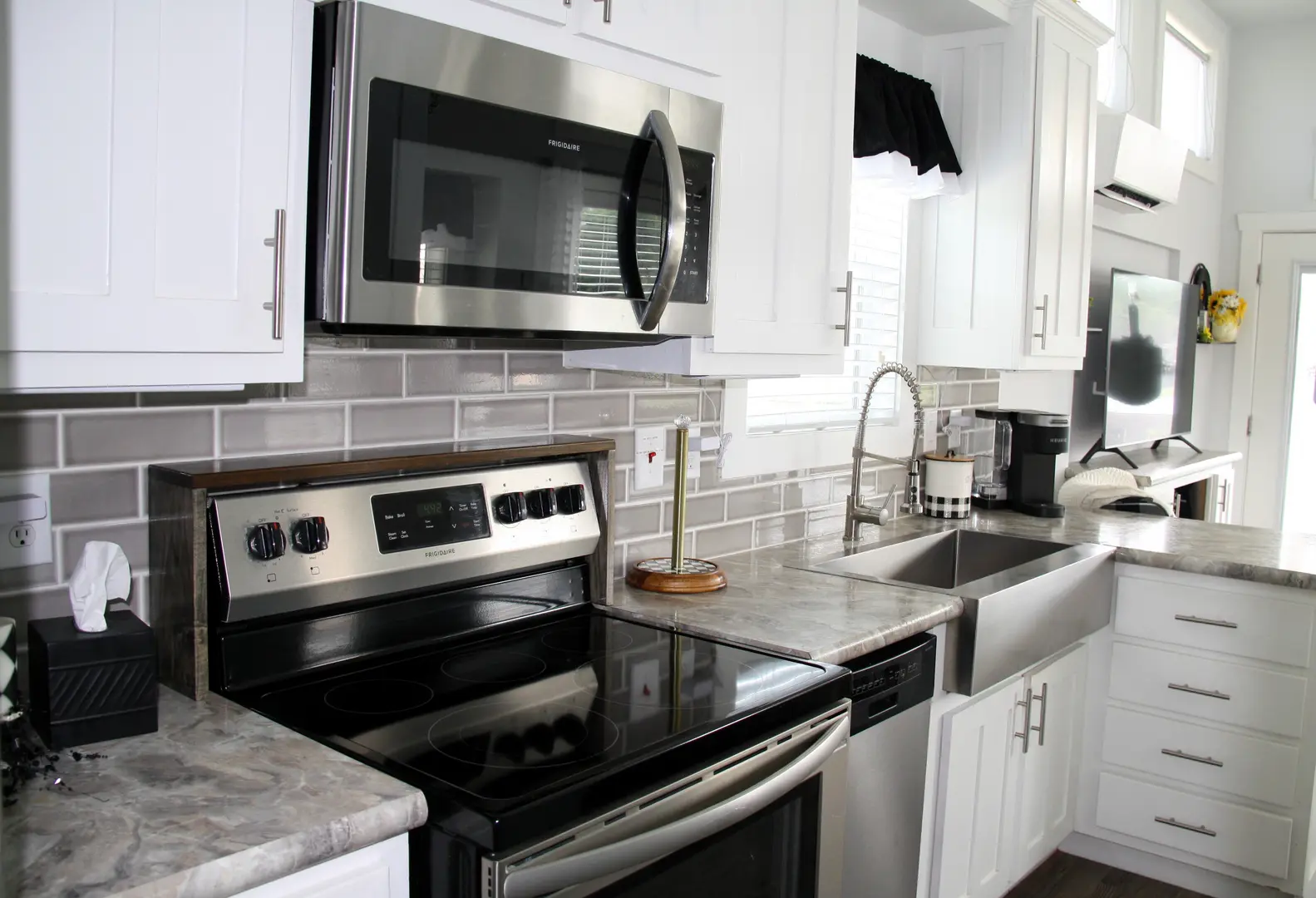 A kitchen with white cabinets and black appliances.