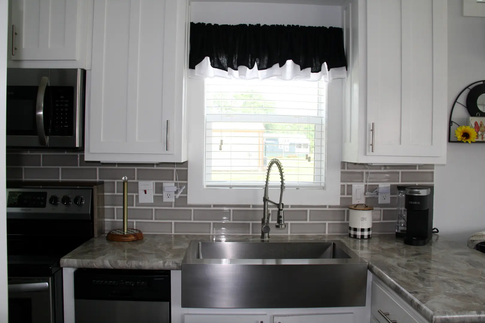 A kitchen with white cabinets and black curtains.