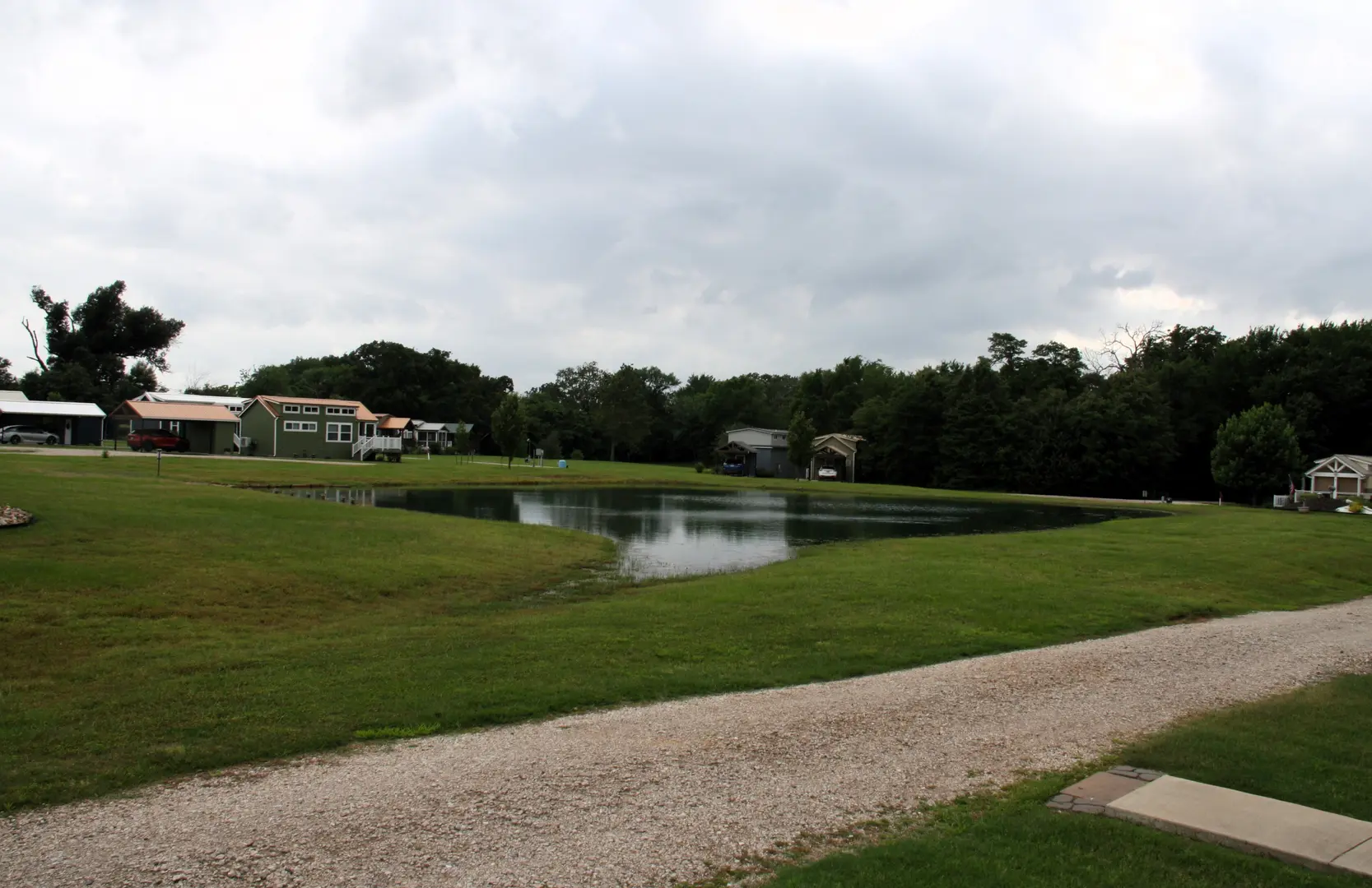 A pond in the middle of a field with houses on either side.