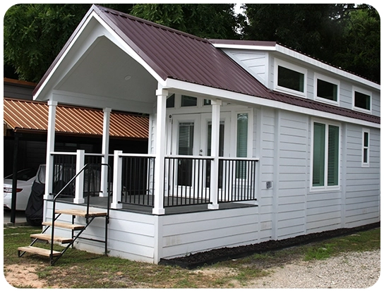 A small white house with a porch and balcony.