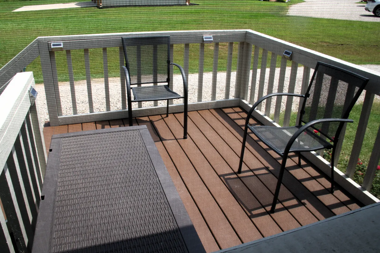 A deck with two chairs and a rug on the ground.