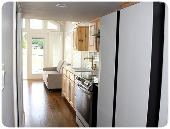 A kitchen with white cabinets and wood floors.