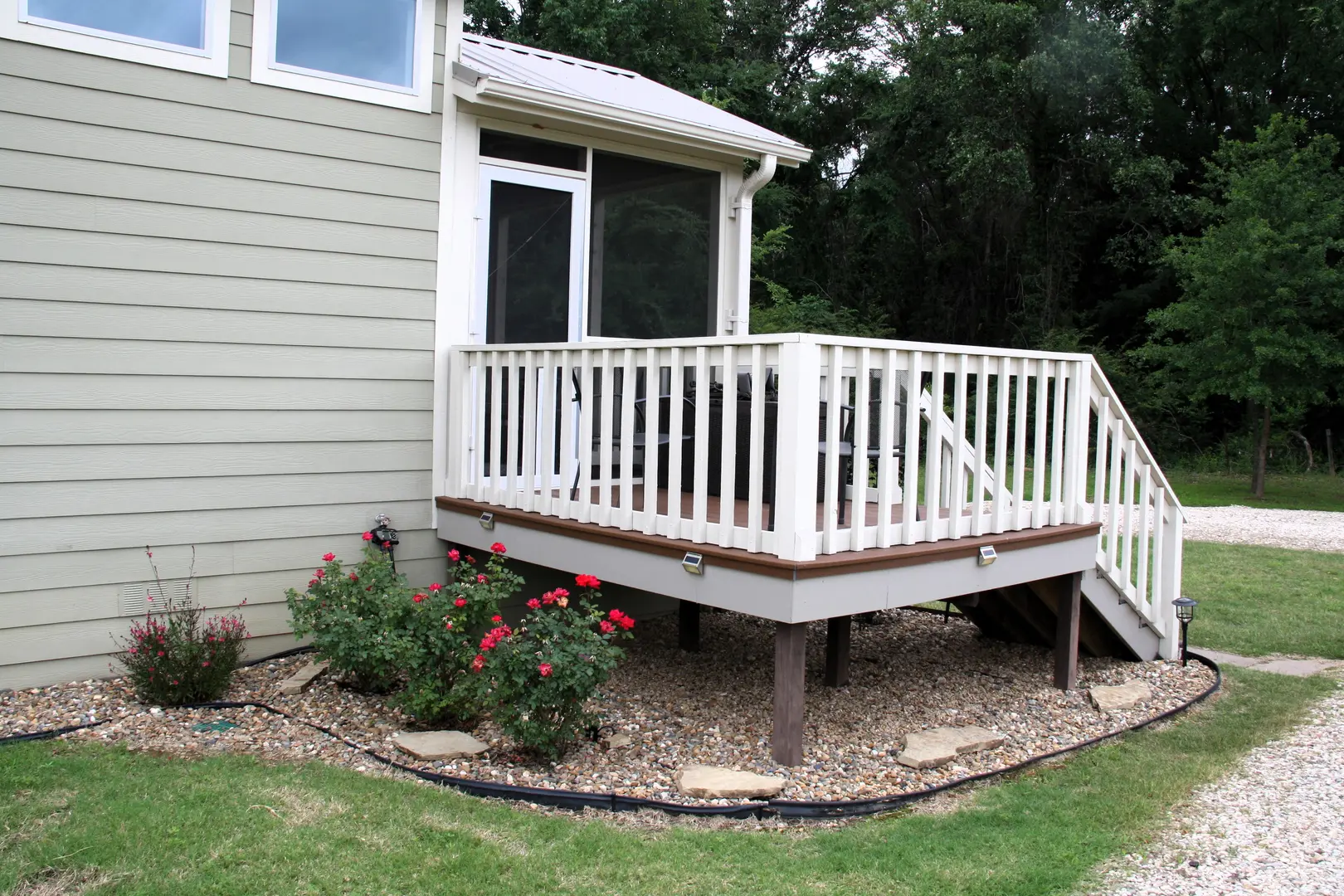 A white deck with flowers in the yard