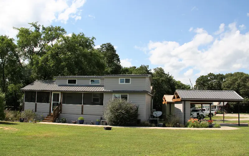 A house with a dog sitting on the lawn