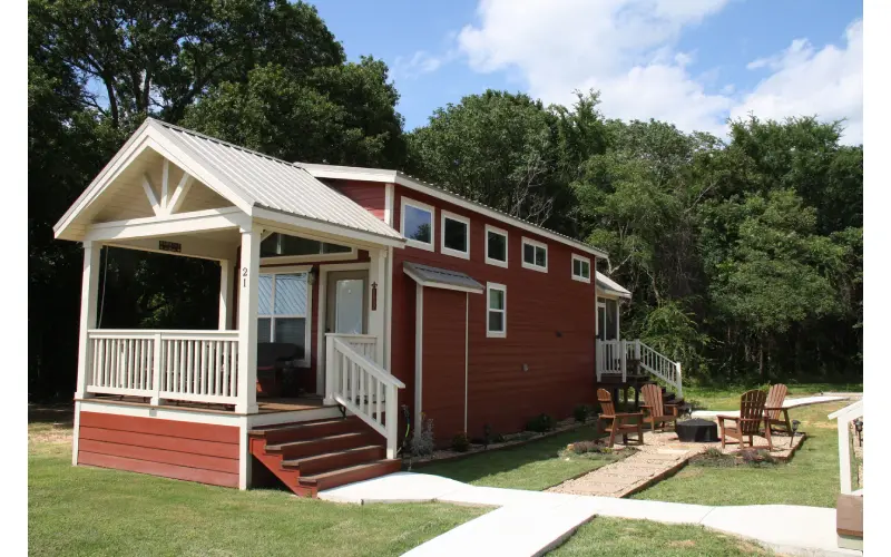 A red house with a porch and deck in front of it.