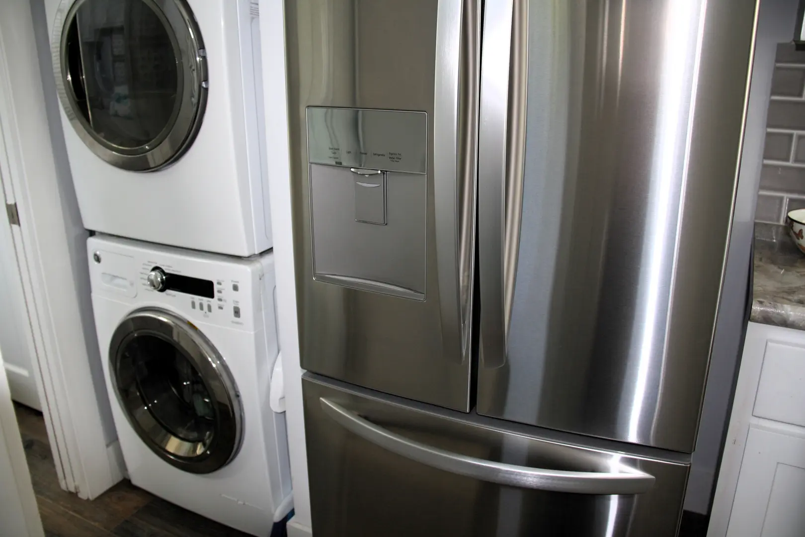 A metallic refrigerator freezer sitting next to a washer.