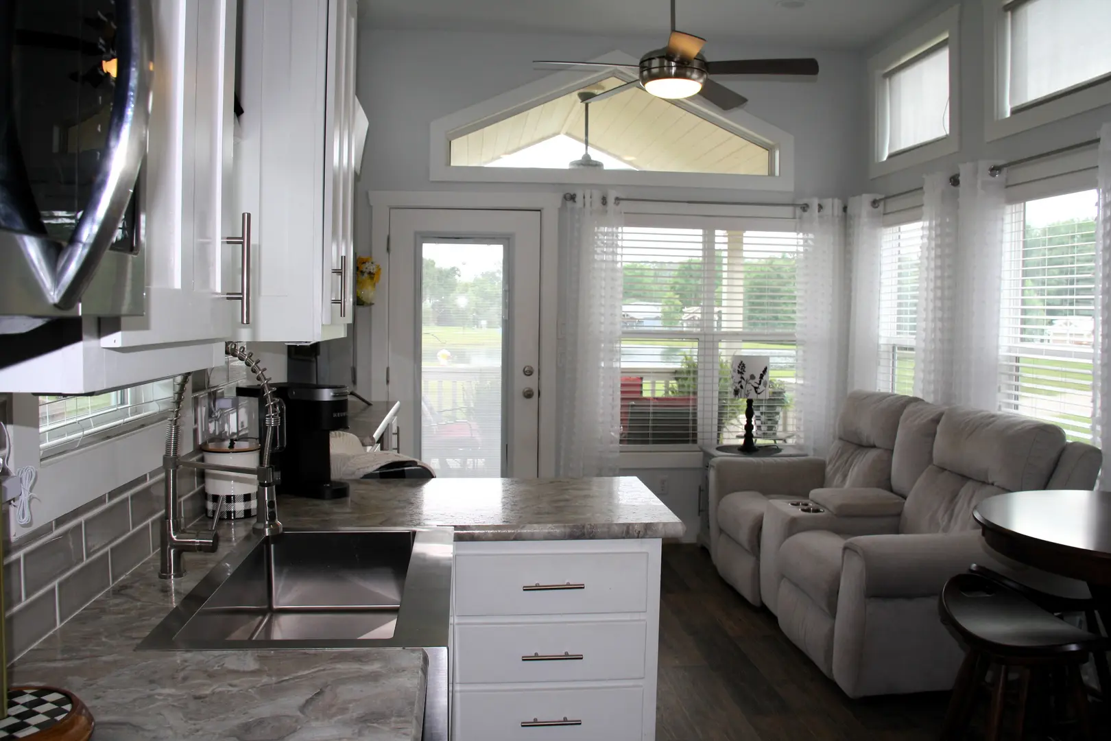 A kitchen with white cabinets and a couch in the middle of it.