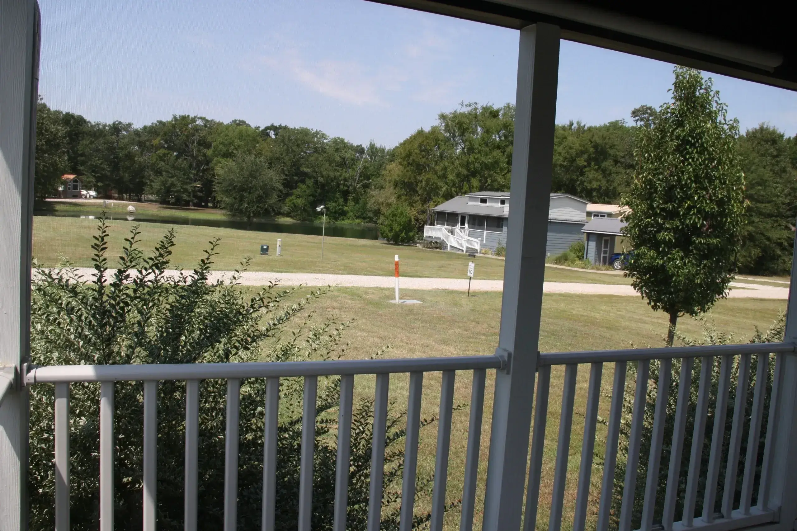 View from porch overlooking grassy yard and trees.