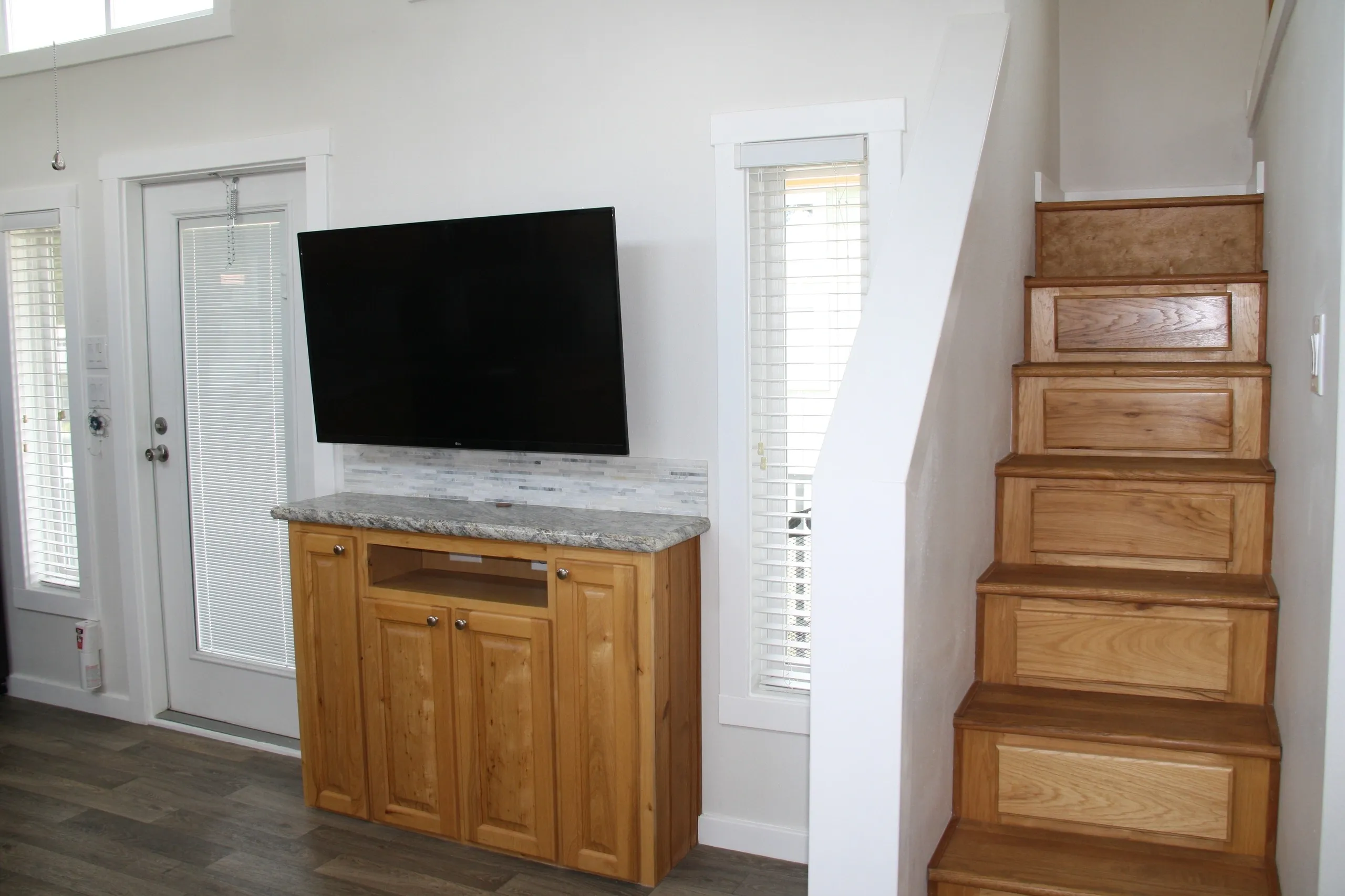 Living room with TV and wooden stairs.