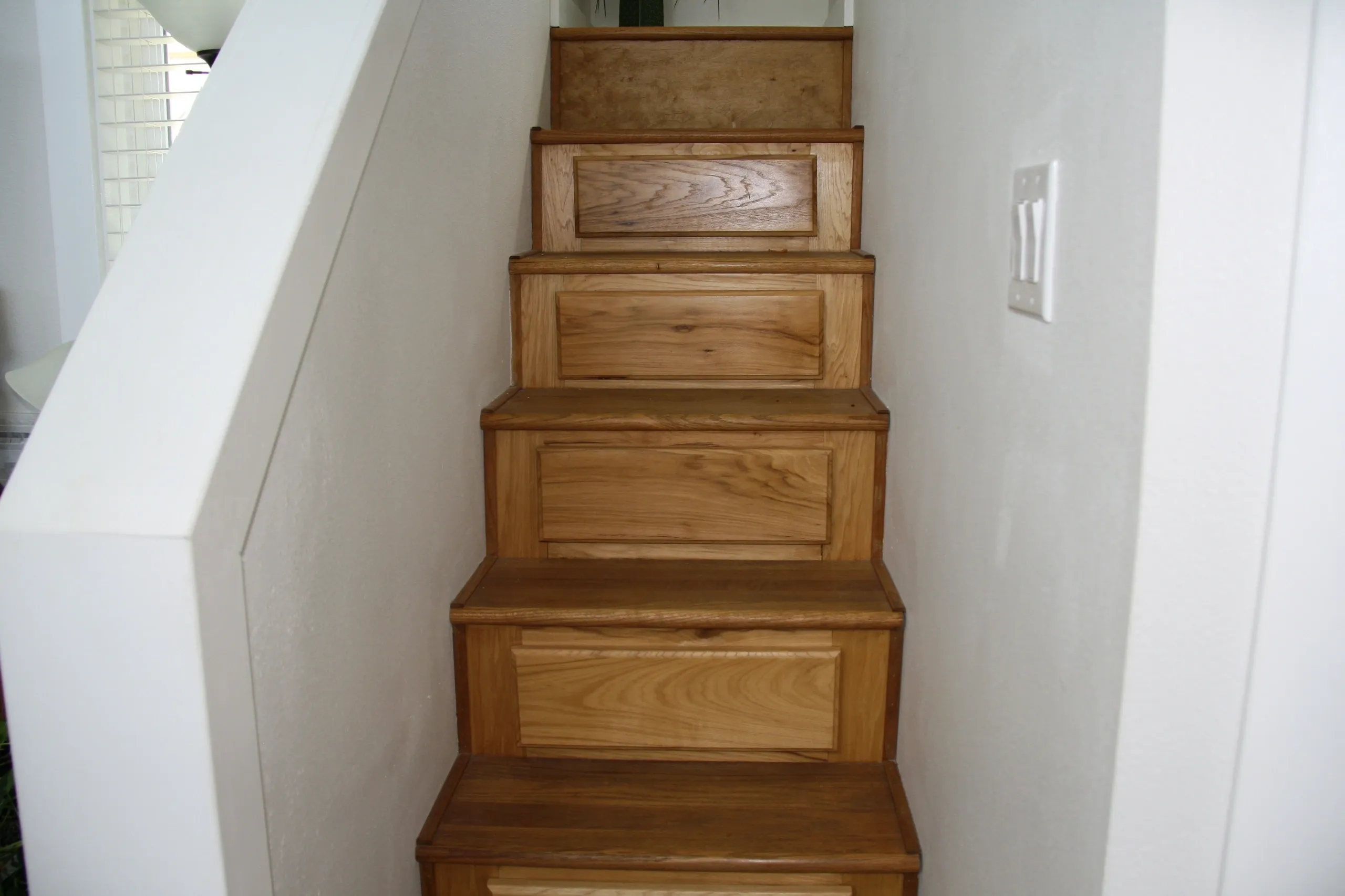 Wooden staircase with white walls.