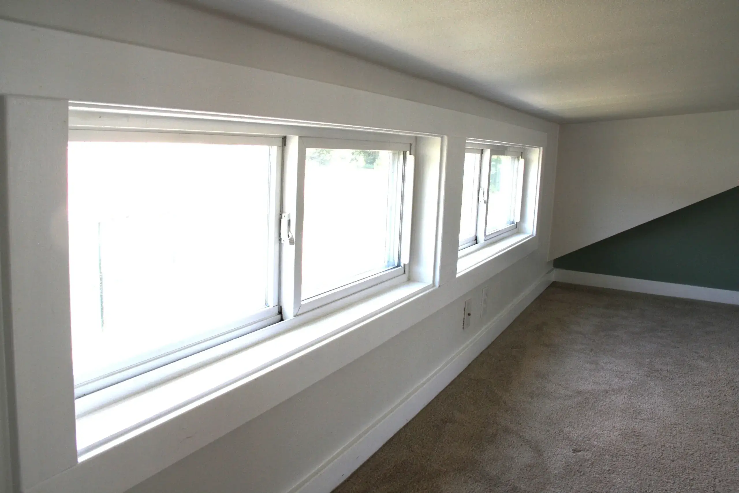 Three rectangular windows in attic room.